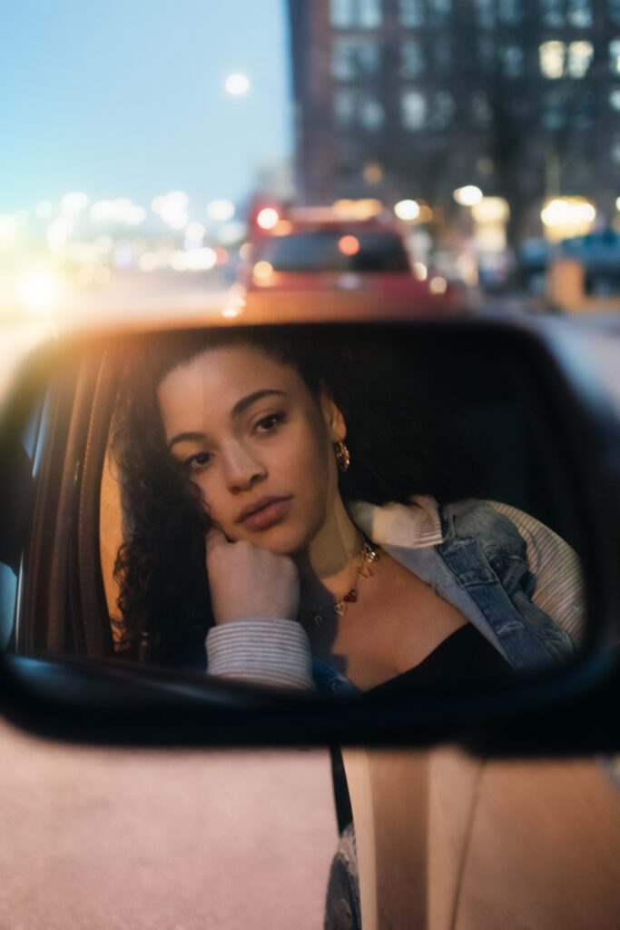 A woman sitting in the passenger seat of her car.