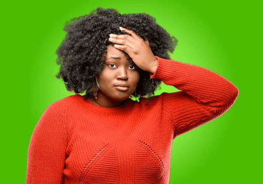 A woman in red sweater holding her head.