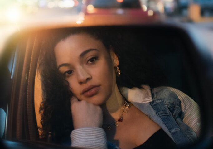 A woman sitting in the passenger seat of her car.