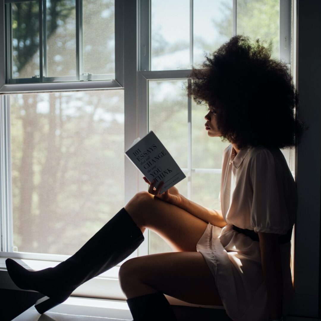 A woman sitting on the floor reading a book.